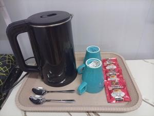 a tray with a coffee pot and utensils on a counter at D'Cabin Roomstay in Sungkai