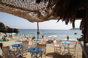 a beach with tables and chairs and people on the beach at Mary's Studios in Agia Pelagia