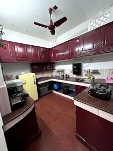 a kitchen with brown cabinets and a ceiling fan at Remasailam Homestay - Thiruvananthapuram , Calm & Blend with Nature in Trivandrum