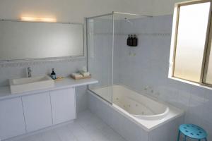 a white bathroom with a tub and a sink at Grandview Holiday Beach House in Gracetown +28 photos