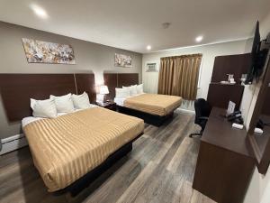 a hotel room with two beds and a desk at Perth Plaza Inn & Suites in Perth