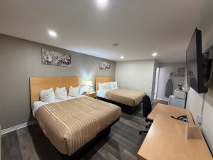 a hotel room with two beds and a desk at Perth Plaza Inn & Suites in Perth