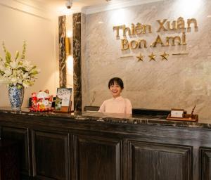a woman standing behind a counter in a hotel lobby at Bon Ami Hotel - Thiên Xuân in Ho Chi Minh City