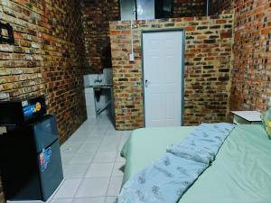 a room with a bed and a brick wall at Acasa do Delco Accommodatiion in Welkom