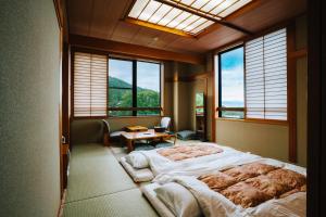 a bedroom with a large bed in a room with windows at ZAO SPA HOTEL Kiraku in Zaō Onsen