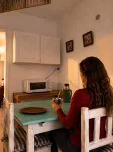 a woman sitting at a table in a kitchen at CASA MENDIOLA, encantadora casa con patio privado, y pileta en jardín cerca de la Laguna in Chascomús
