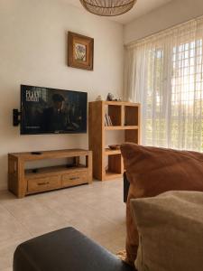 a living room with a flat screen tv on the wall at CASA MENDIOLA, encantadora casa con patio privado, y pileta en jardín cerca de la Laguna in Chascomús