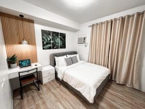 a bedroom with a bed and a desk with a computer at Zara at Mesavirre Bacolod in Bacolod
