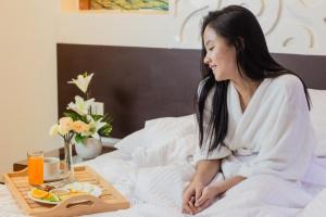 a woman sitting on a bed with a tray of food at Eurotel Boracay in Boracay +29 photos