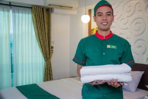 a man holding a stack of towels in a hotel room at Eurotel Boracay in Boracay