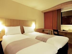a hotel room with two beds and a desk at ibis Arapiraca in Arapiraca