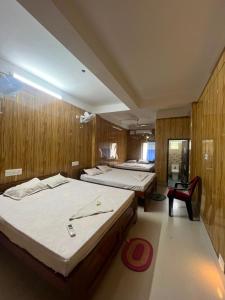 three beds in a room with wooden walls at Panthanibas momochitte in Bakkhali