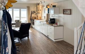 a kitchen with white cabinets and a table and a chair at 3 Bedroom Nice Home In Os in Oma