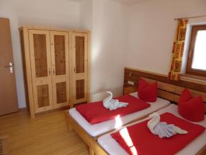 - une chambre avec 2 lits dotés d'oreillers rouges et blancs dans l'établissement Birnhornblick, à Leogang