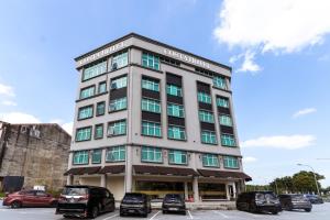 a tall building with cars parked in a parking lot at Costa Hotel Nilai in Nilai