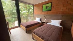 a hotel room with two beds and a window at SAMAY FOREST- MASHPI AMAGUSa in Mashpi
