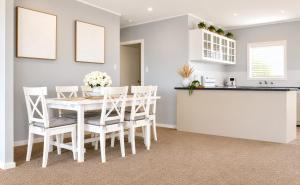 a kitchen and dining room with a white table and chairs at Anita Cottage waterfront in Lake Munmorah +13 photos