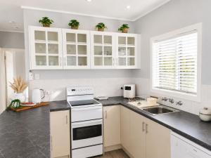 a kitchen with white cabinets and a sink at Anita Cottage waterfront in Lake Munmorah