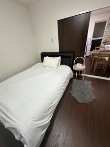 a bedroom with a large white bed and a table at Panda Home Umeda 01 in Osaka