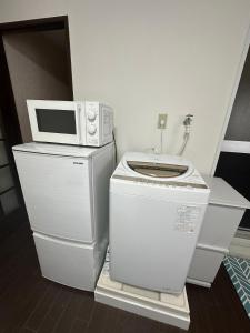 a microwave sitting on top of a washing machine at Panda Home Umeda 01 in Osaka