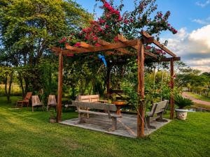 a wooden pergola with a bench and a table with flowers at Rancho ABA DO BETIONE in Bodoquena
