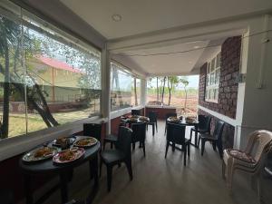 a restaurant with tables and chairs and a large window at Siddhi farm in Kolhapur