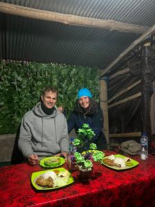 a man and woman sitting at a table with food at Batur Sunrise Tent in Kubupenlokan