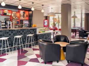 a restaurant with a bar with chairs and a counter at Hôtel Mercure Marne-la-Vallée Bussy St Georges in Bussy-Saint-Georges