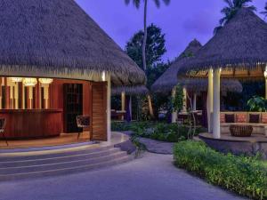 a resort with thatched huts and a table and chairs at Mercure Maldives Kooddoo - Adults-Only Escape in Maamendhoo