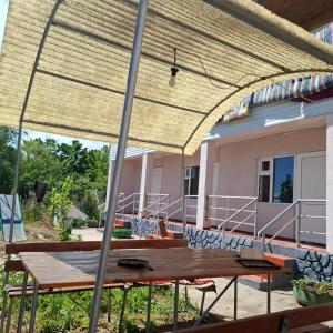 a picnic table under a straw roof on a house at Гостевой дом in Cholpon-Ata