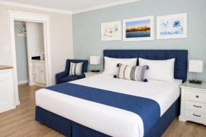 a blue and white bedroom with a bed and a chair at Coronado Inn in San Diego