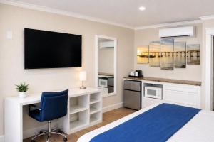 a bedroom with a bed and a desk and a tv at Coronado Inn in San Diego
