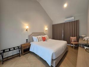 a bedroom with a large white bed and a chair at DRIZZLE pool and pillows in Phra Khanong