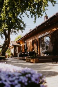 a wooden house with a tree and some purple flowers at STACJA RUDA in Złota Wieś
