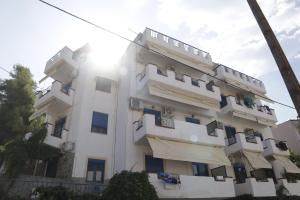 a white apartment building with the sun in the background at Egeon Studios in Neos Marmaras