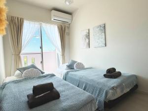 two beds in a room with towels on them at Maison deLacue in Uruma