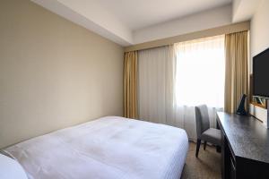 a hotel room with a bed and a desk and a window at KKR Hotel Nagoya in Nagoya
