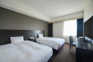a hotel room with two beds and a television at KKR Hotel Nagoya in Nagoya