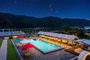a pool with tables and umbrellas at night at Gapyeong the Bay Resort in Gapyeong