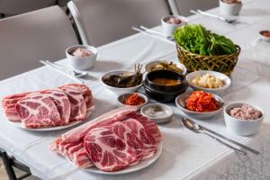 a table topped with plates of meat and bowls of dips at Gapyeong the Bay Resort in Gapyeong