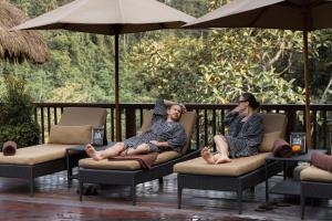 a group of people sitting on a porch with umbrellas at Nandini Jungle by Hanging Gardens in Payangan