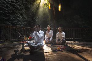 a group of three people sitting on a wooden deck at Nandini Jungle by Hanging Gardens in Payangan