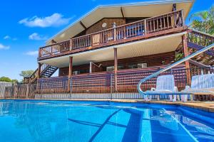 a house with a balcony and a swimming pool at Boat Harbour Stays in Hervey Bay