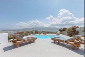 a swimming pool with two benches and a view of the ocean at Morning glow villa in Antiparos