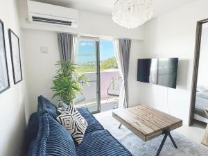 a living room with a blue bed and a table at Maison deLacue in Uruma