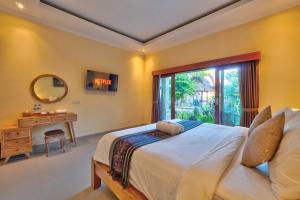 a bedroom with a bed and a desk and a window at Aruna House in Ubud
