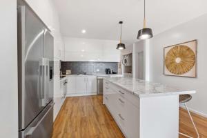 a kitchen with white cabinets and a stainless steel refrigerator at Sophisticated & stylish beachside apartment with pool in Sunrise Beach
