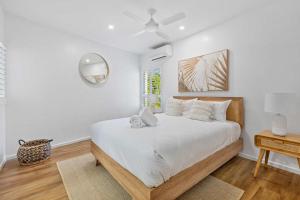 a bedroom with a bed with white sheets and a mirror at Sophisticated & stylish beachside apartment with pool in Sunrise Beach