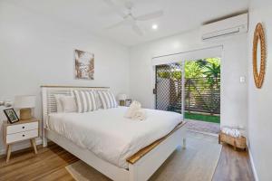 a white bedroom with a bed and a window at Sophisticated & stylish beachside apartment with pool in Sunrise Beach