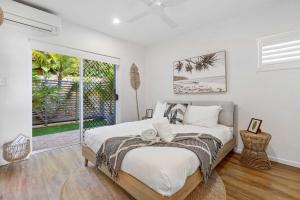 a bedroom with a bed and a large window at Sophisticated & stylish beachside apartment with pool in Sunrise Beach +8 photos
